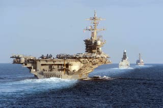 The USS Abraham Lincoln aircraft carrier (L) transits the Strait of Hormuz on November 19, 2019